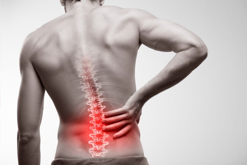 A person holding their lower back in discomfort