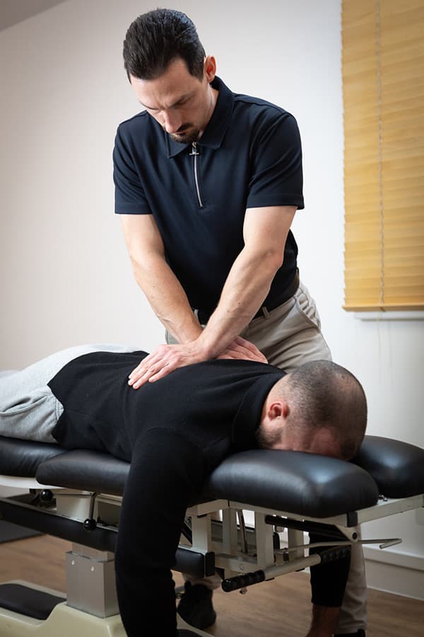 Dr Elliot Ward standing beside the treatment table with a patient