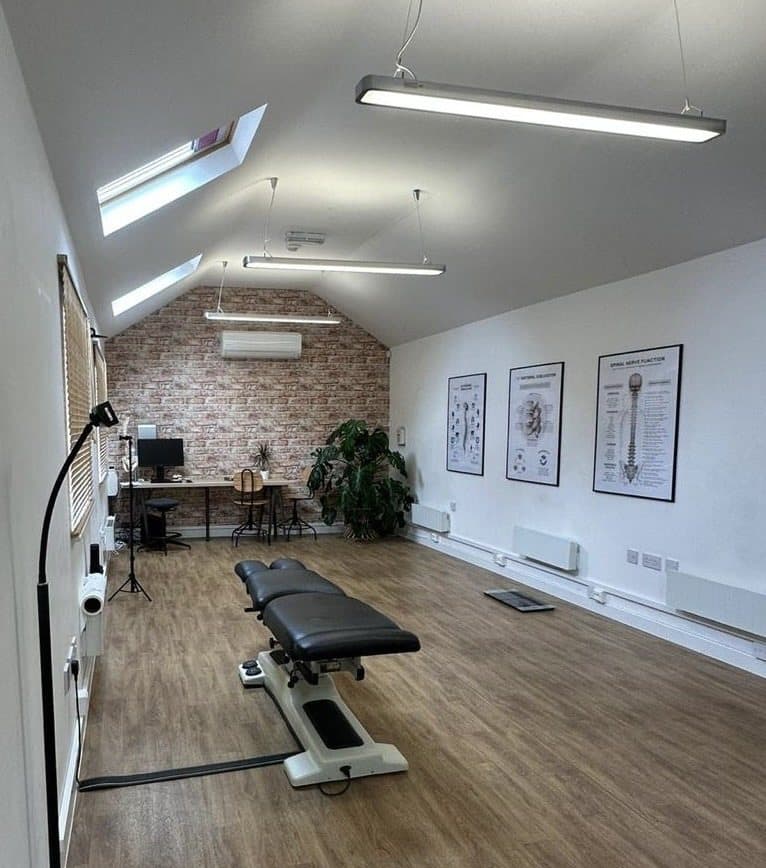 The treatment room with the table, posture charts and a brick wall